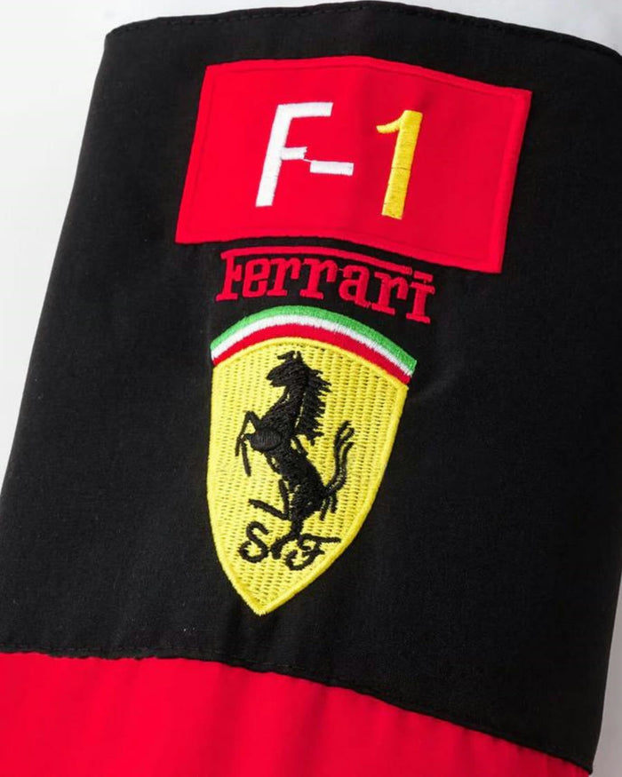 Manga preta com patch F-1 vermelho, nome em arco e escudo amarelo