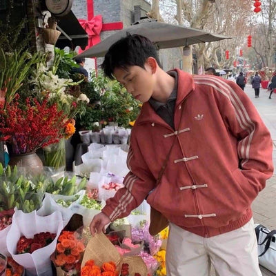 Jaqueta vermelha escolhida entre baldes de flores, numa banca de rua
